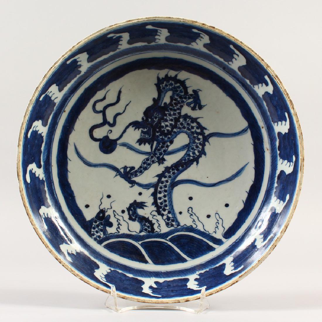 A CHINESE CIRCULAR DISH, painted in blue and white with: A CHINESE CIRCULAR DISH, painted in blue and white with a dragon. 28.5cms diameter.