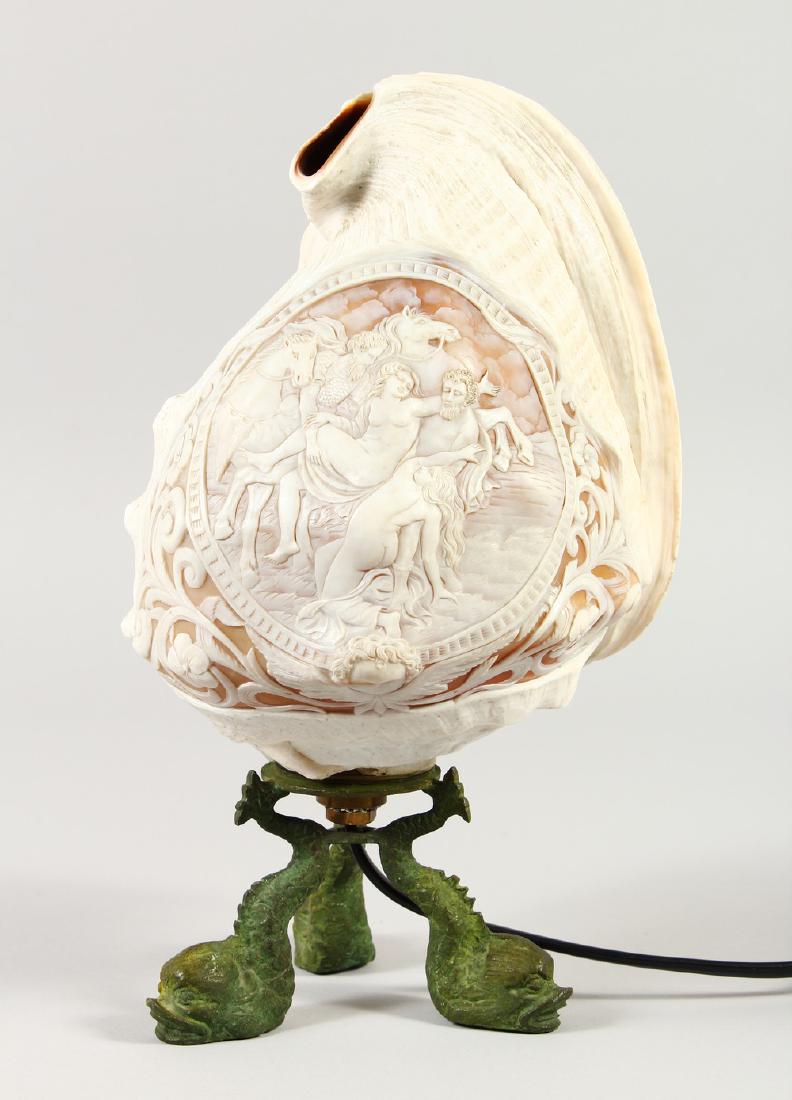A SUPERB QUALITY CAMEO SHELL LAMP carved with a: A SUPERB QUALITY CAMEO SHELL LAMP carved with a classical scene, nudes, men and horses, supported on three gilt metal dolphin feet.