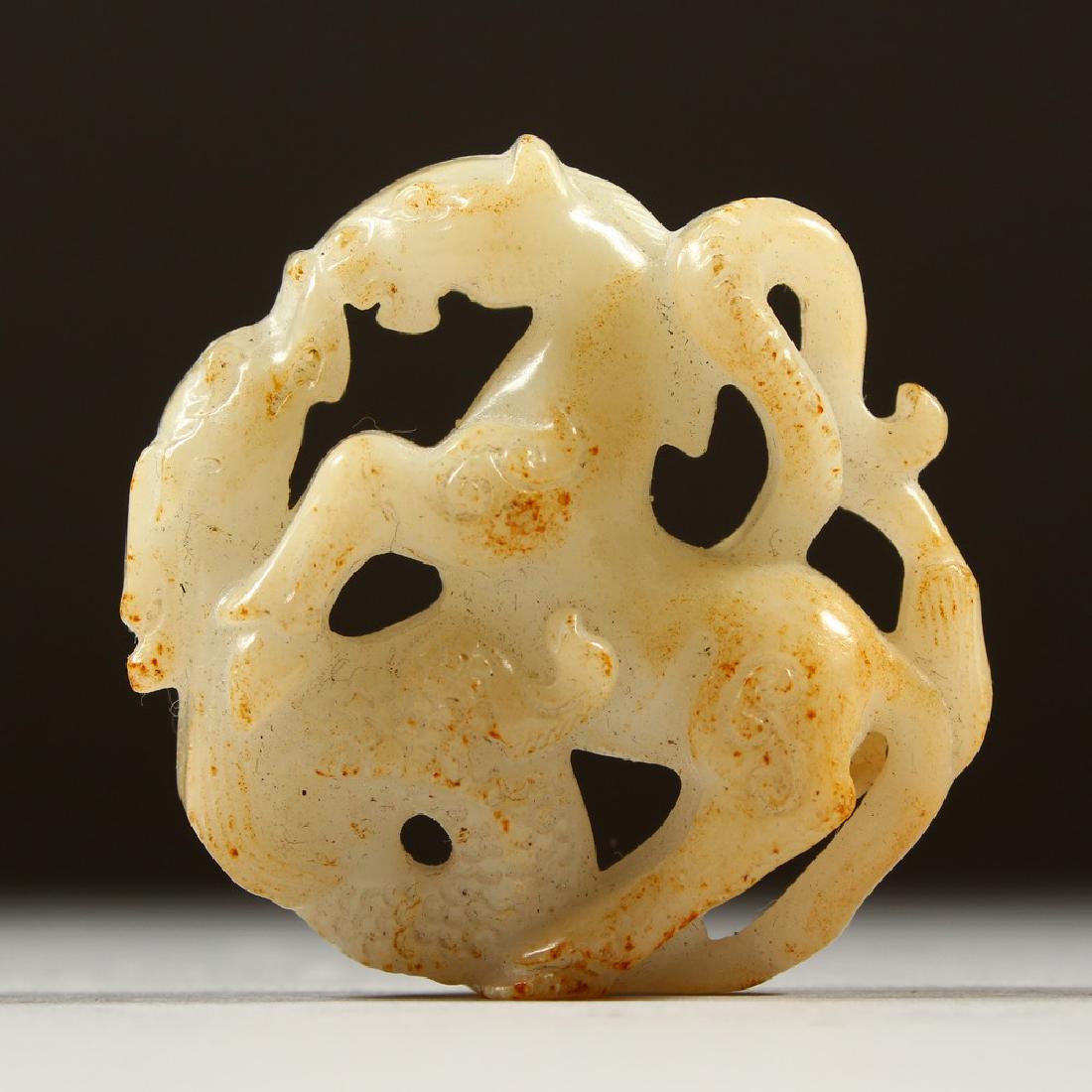 A PIERCED AND CARVED WHITE JADE PENDANT, carved as a: A PIERCED AND CARVED WHITE JADE PENDANT, carved as a horse and dragon. 5cms diameter.
