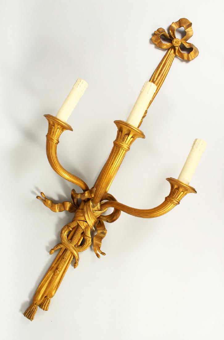 A LARGE SET OF FIVE THREE LIGHT WALL SCONCES, with: A LARGE SET OF FIVE THREE LIGHT WALL SCONCES, with curving trumpets and ribbon motifs. 114cms long.