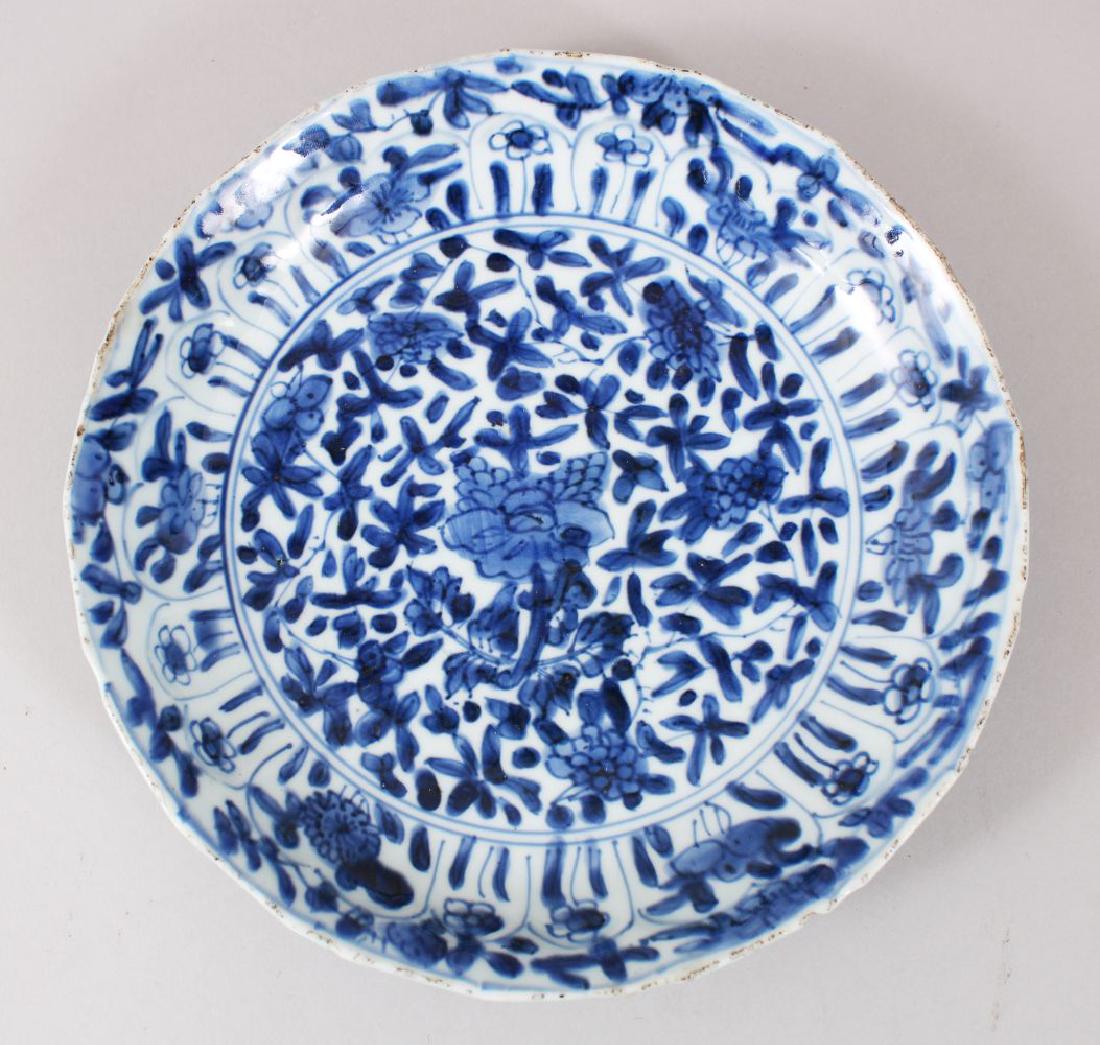 A GOOD CHINESE BLUE & WHITE KANGXI PORCELAIN PLATE,: A GOOD CHINESE BLUE & WHITE KANGXI PORCELAIN PLATE, with a moulded rim and decorated with formal floral decor, the base with a ribboned emblem mark, 21.5cm diameter.