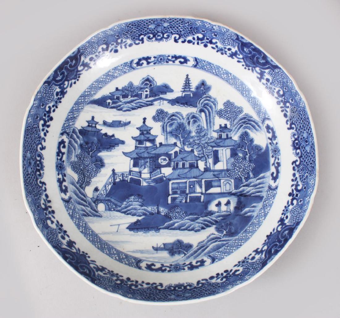 AN 18TH / 19TH CENTURY CHINESE BLUE & WHITE PORCELAIN: AN 18TH / 19TH CENTURY CHINESE BLUE & WHITE PORCELAIN SCALLOPED DISH, decorated with scenes of landscapes and formal borders, 24cm diameter.