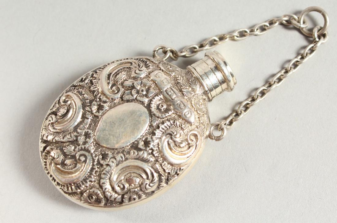 A VICTORIAN SCENT BOTTLE repousse with flowers and: A VICTORIAN SCENT BOTTLE repousse with flowers and scrolls on a chai. London 1869. Maker George Unite.