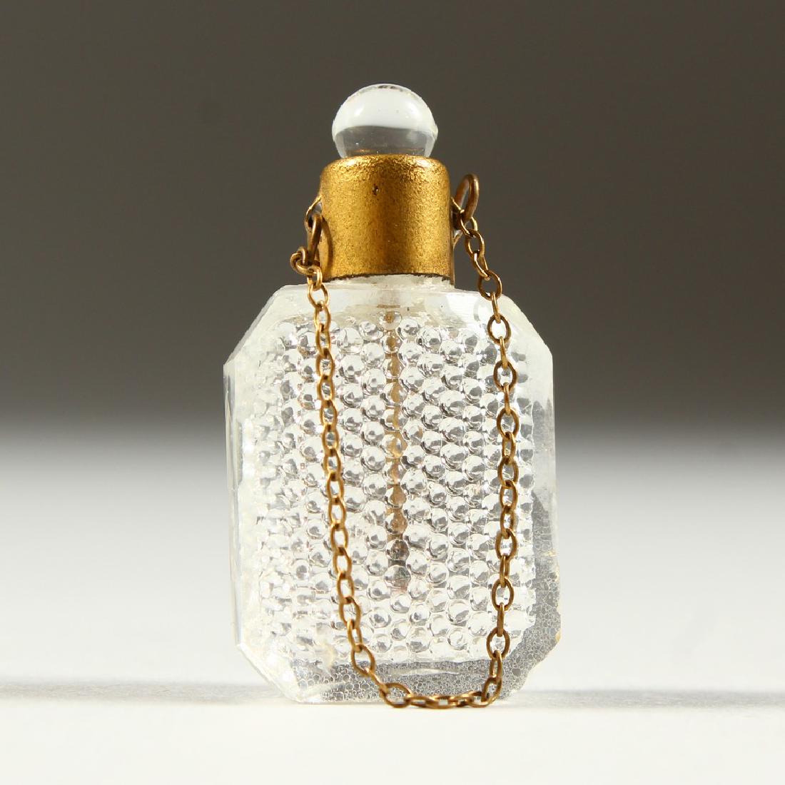 A TINY CUT GLASS SCENT BOTTLE AND STOPPER on a chain.: A TINY CUT GLASS SCENT BOTTLE AND STOPPER on a chain. 3.5cms.