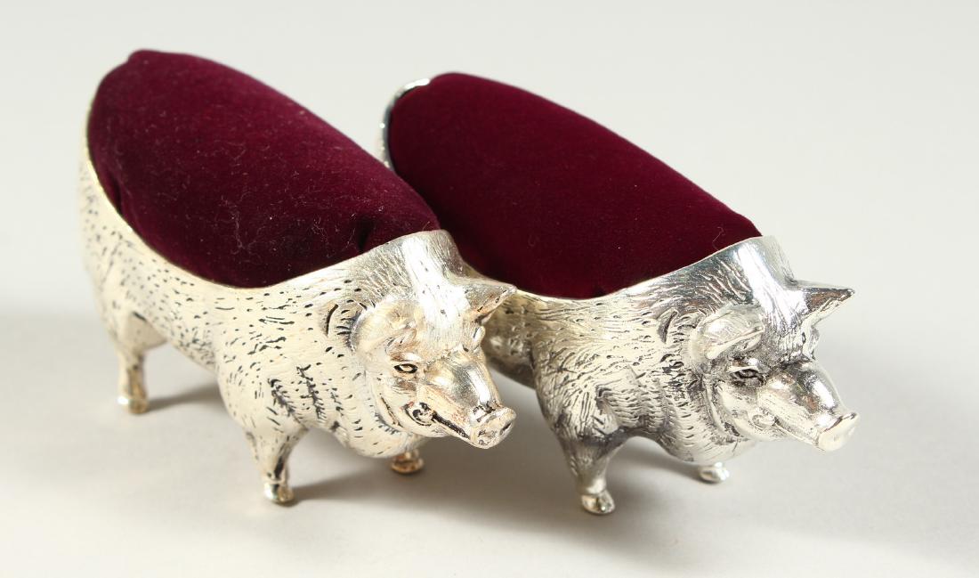 A LARGE PAIR OF .800 PIG PIN CUSHIONS with blue velvet.: A LARGE PAIR OF .800 PIG PIN CUSHIONS with blue velvet. 10cms long.