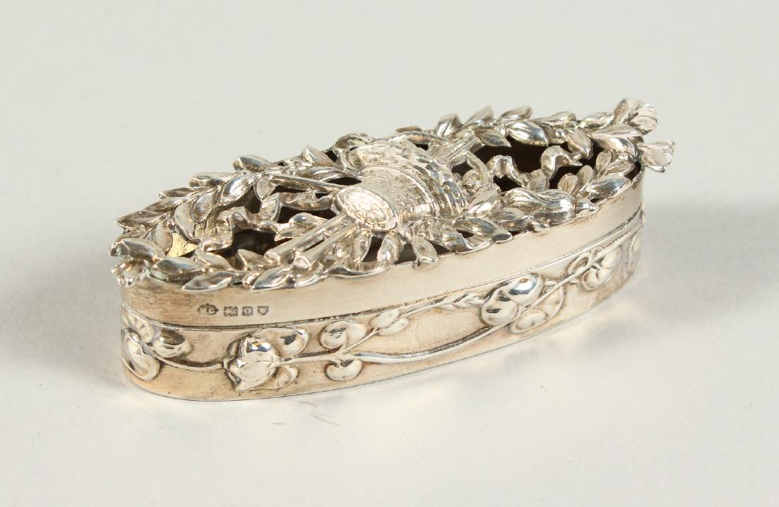 AN EDWARD VII OVAL BOX AND COVER, pierced with laurel: AN EDWARD VII OVAL BOX AND COVER, pierced with laurel and musical trophies. London 1909. Maker William Comyns. 3.25ins long.