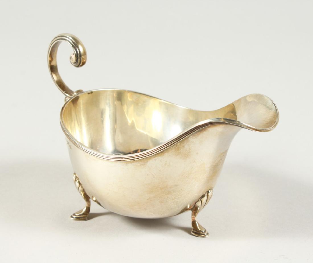 A SAUCEBOAT with reeded edges, scroll handle on three: A SAUCEBOAT with reeded edges, scroll handle on three pad feet. Sheffield 1925. Maker Walker and Hall.