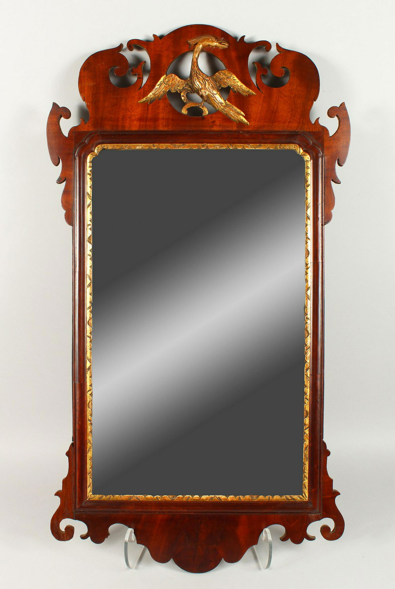 A GEORGIAN STYLE MAHOGANY FRETWORK FRAMED WALL MIRROR,: A GEORGIAN STYLE MAHOGANY FRETWORK FRAMED WALL MIRROR, with ho-ho bird crest. 86cms high x 47cms wide.