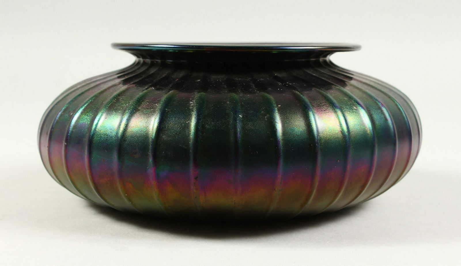 A LOETZ TYPE CIRCULAR IRIDESCENT BOWL with ribbed: A LOETZ TYPE CIRCULAR IRIDESCENT BOWL with ribbed decoration. 21cms diameter.