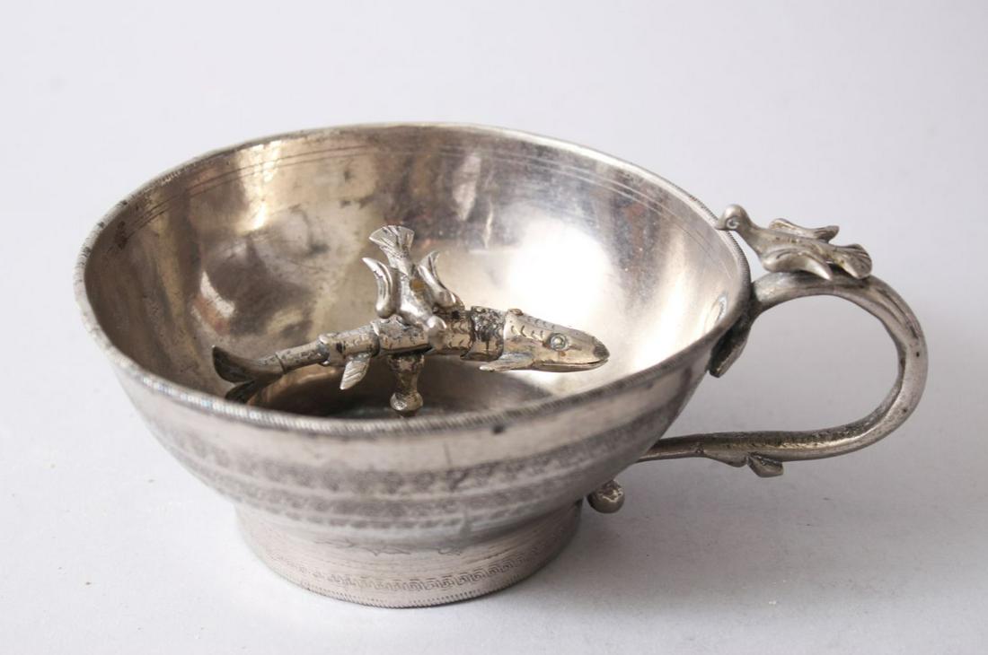 A 19TH CENTURY ARMENIAN SILVERED CUP WITH RETICULATED: A 19TH CENTURY ARMENIAN SILVERED CUP WITH RETICULATED FISH, the andle with a bird, the interior with a reticulated fish, the interior of the base with a roundel of script, 12cm diam.