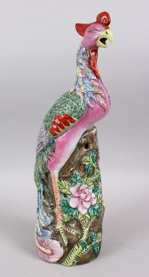 A 19TH / 20TH CENTURY CHINESE FAMILLE ROSE PORCELAIN: A 19TH / 20TH CENTURY CHINESE FAMILLE ROSE PORCELAIN FIGURE OF A PHOENIX BIRD, stood on a naturalistic wood outcrop laced with flora, with its mouth open, 44cm high x 13cm wide.