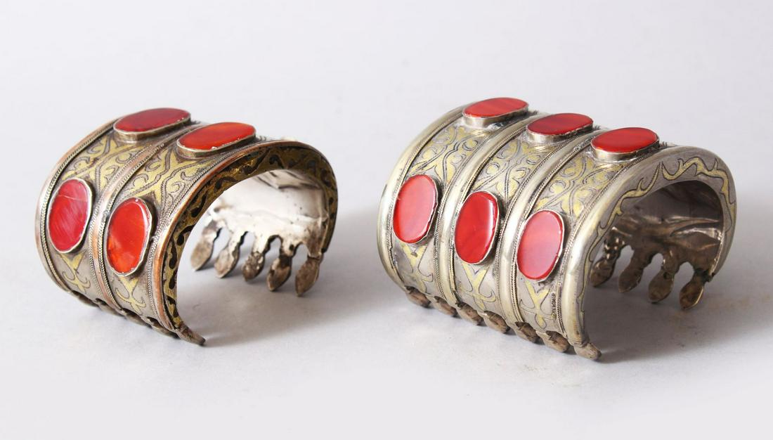 TWO GOOD 19TH / 20TH CENTURY CARNELIAN INSET SILVER &: TWO GOOD 19TH / 20TH CENTURY CARNELIAN INSET SILVER & GILT TURKMEN BRACELETS, the bracelets each with oval inset hardstone, both 5cm high x 8cm wide