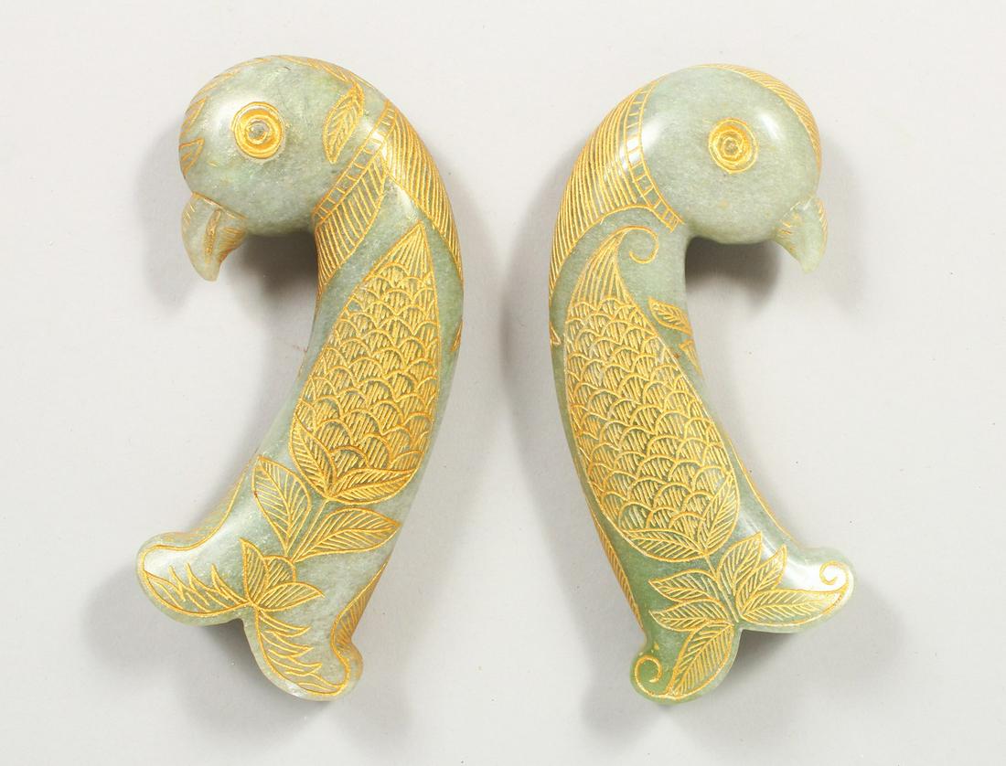 A GOOD PAIR OF EARLY 20TH CENTURY INDIAN / PERSIAN: A GOOD PAIR OF EARLY 20TH CENTURY INDIAN / PERSIAN CARVED JADE DAGGER KHANJAR HANDLE, the body of the curving handle in the form of a parrot and chased floral decoration and then highlighted with gilt