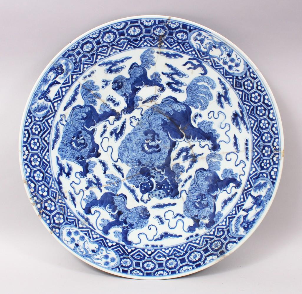 A LARGE 19TH CENTURY CHINESE BLUE & WHITE PORCELAIN: A LARGE 19TH CENTURY CHINESE BLUE & WHITE PORCELAIN CHARGER OF LION DOGS, the charger completely repaired, depicting multiple lion dogs amongst stylized clouds and waves, 49cm diameter.