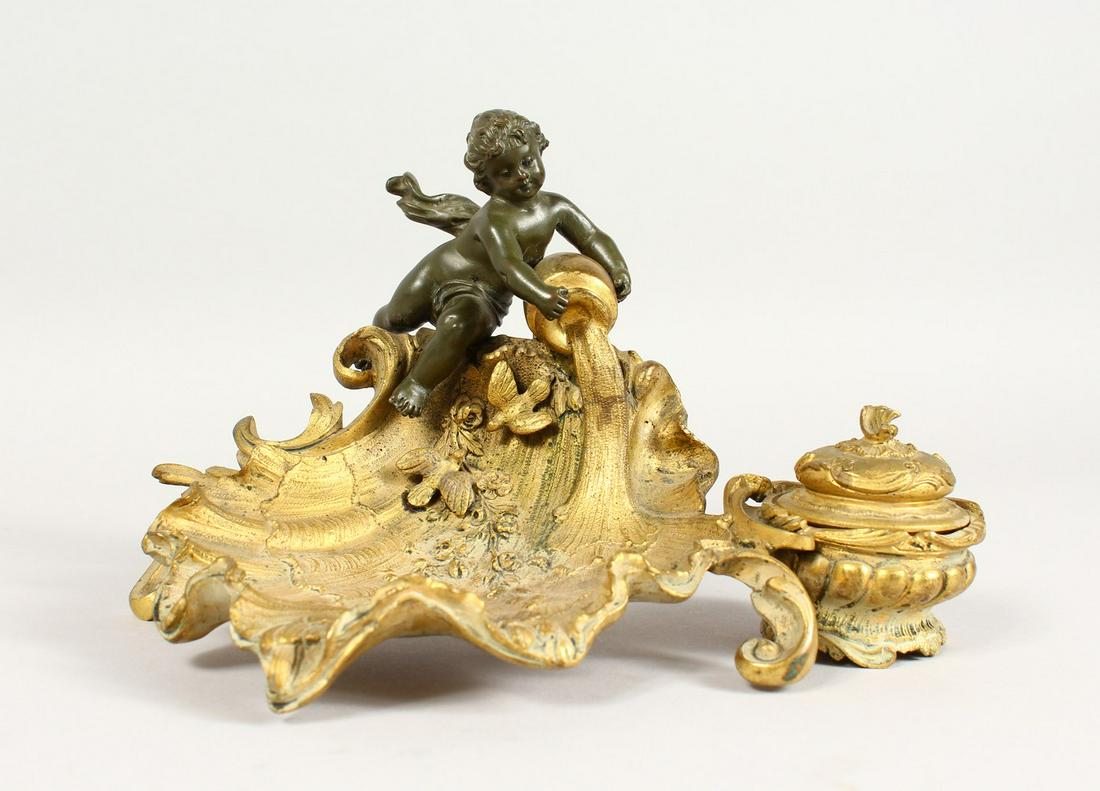A SUPERB LINKE MODEL GILDED BRONZE SHELL SHAPED: A SUPERB LINKE MODEL GILDED BRONZE SHELL SHAPED INKWELL, with bronze cupid with a ewer, with flowers and birds. 9ins long x 5.5ins high.
