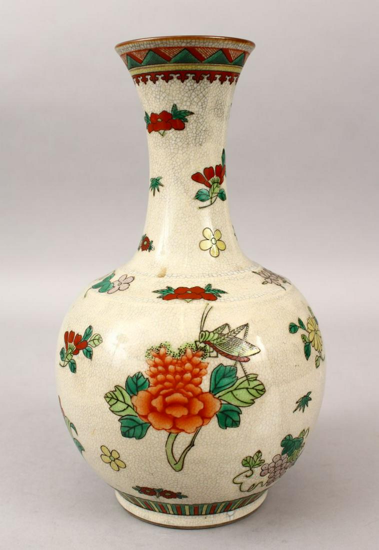 A 20TH CENTURY CHINESE FAMILLE ROSE CRACKLE GLAZED: A 20TH CENTURY CHINESE FAMILLE ROSE CRACKLE GLAZED PORCELAIN BOTTLE VASE, the body decorated with insects and flora upon a crackle glaze, with an iron red mark to the base, 28.5cm high.