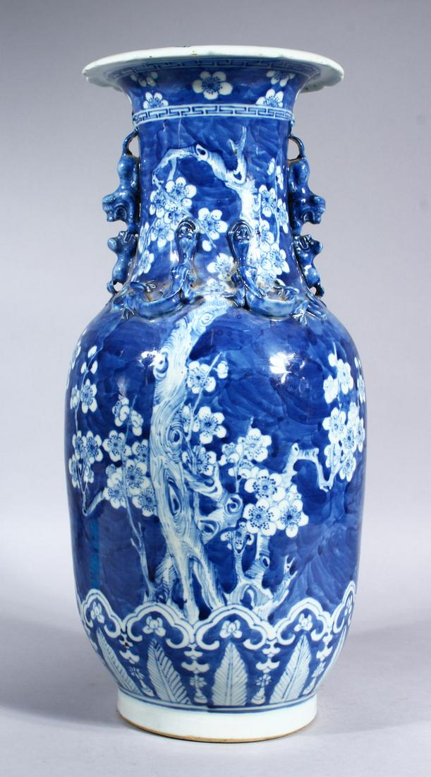 A 19TH CENTURY CHINESE BLUE & WHITE PORCELAIN PRUNUS: A 19TH CENTURY CHINESE BLUE & WHITE PORCELAIN PRUNUS VASE, the body of the vase decorated with scenes of prunus blossom above a border of ruyi head and stiff lappet, with moulded lion dog handles and 