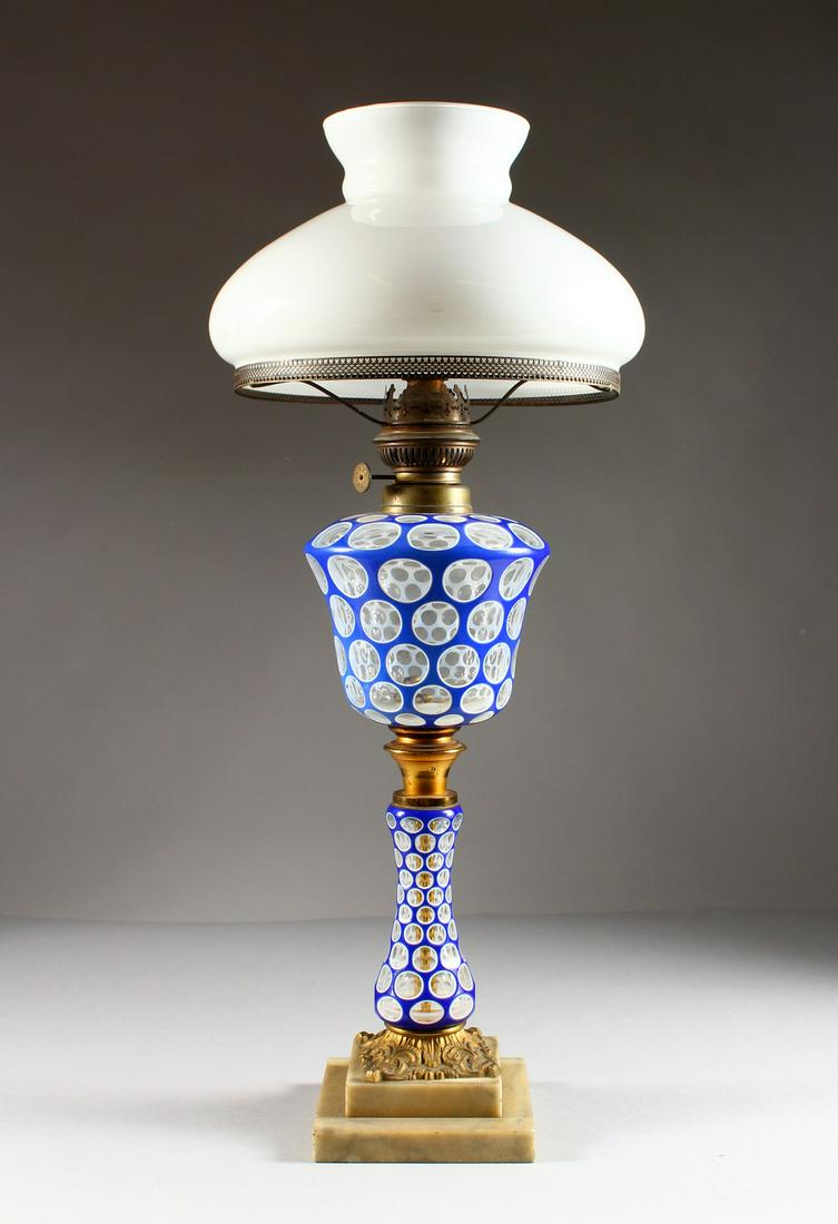 A 19TH CENTURY BOHEMIAN BLUE AND WHITE OVERLAY OIL: A 19TH CENTURY BOHEMIAN BLUE AND WHITE OVERLAY OIL LAMP, with reservoir and stem, with white glass shade.