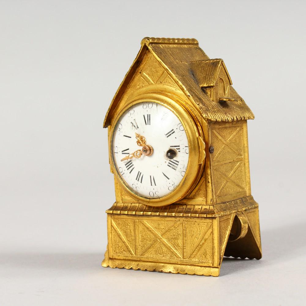 A MINIATURE ORMOLU CLOCK, modelled as a half timbered: A MINIATURE ORMOLU CLOCK, modelled as a half timbered building with thatched roof. 3.25ins high.