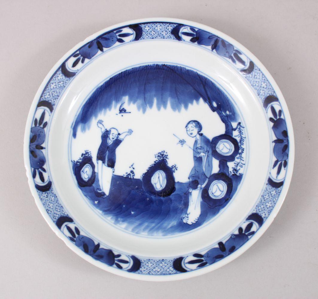 A 19TH CENTURY CHINESE BLUE & WHITE PORCELAIN PLATE,: A 19TH CENTURY CHINESE BLUE & WHITE PORCELAIN PLATE, the decoration depicting two men in a garden setting, the base with further decoration of implements, the base with a mark with double blue rings, 