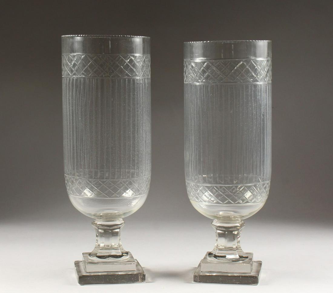 A PAIR OF CUT GLASS STORM LAMPS, on square stepped: A PAIR OF CUT GLASS STORM LAMPS, on square stepped bases. 1ft 4ins high.