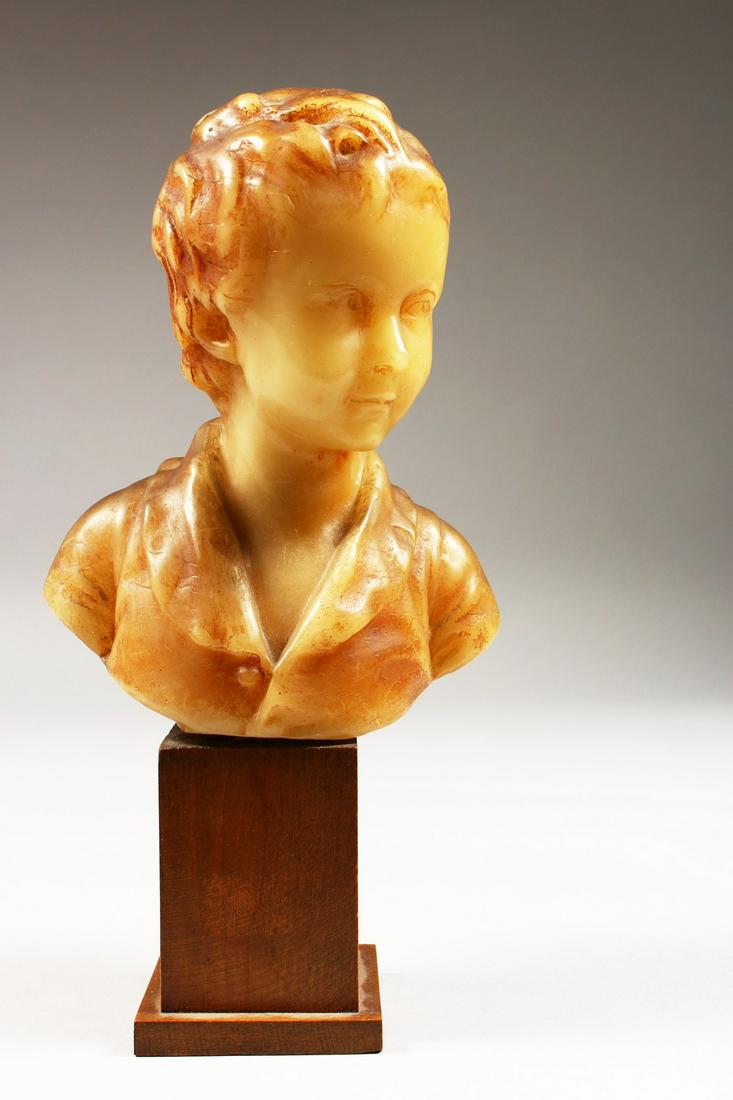 A SMALL GEORGIAN CARVED WAX BUST, head and shoulders of: A SMALL GEORGIAN CARVED WAX BUST, head and shoulders of a young boy. 6ins high on a wooden plinth.
