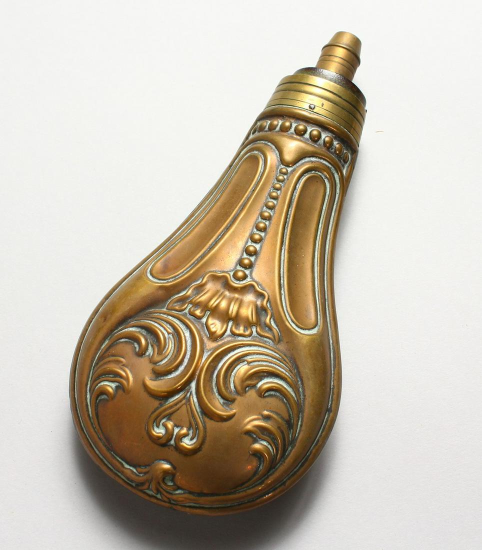 A COPPER POWDER FLASK, embossed with scrolling foliage.: A COPPER POWDER FLASK, embossed with scrolling foliage. 6.75ins.