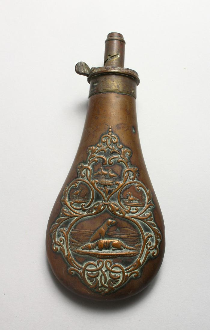 A COPPER POWDER FLASK by JAMES DIXON, one side embossed: A COPPER POWDER FLASK by JAMES DIXON, one side embossed with four panels, the largest with two hunting dogs, the remaining smaller panels with game birds. 7.75ins. Spring partly lacking.