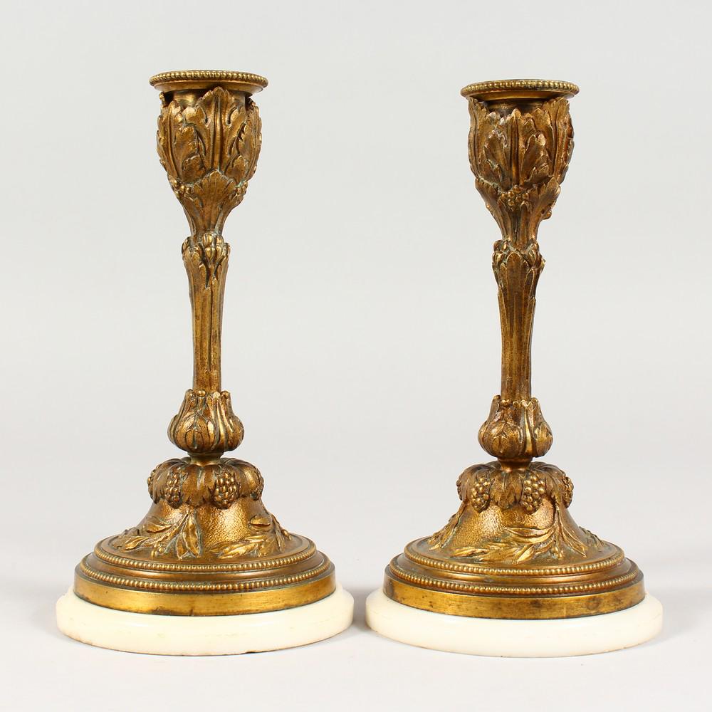 A SMALL PAIR OF ORMOLU CANDLESTICKS, on circular marble: A SMALL PAIR OF ORMOLU CANDLESTICKS, on circular marble bases. 6.75ins high.