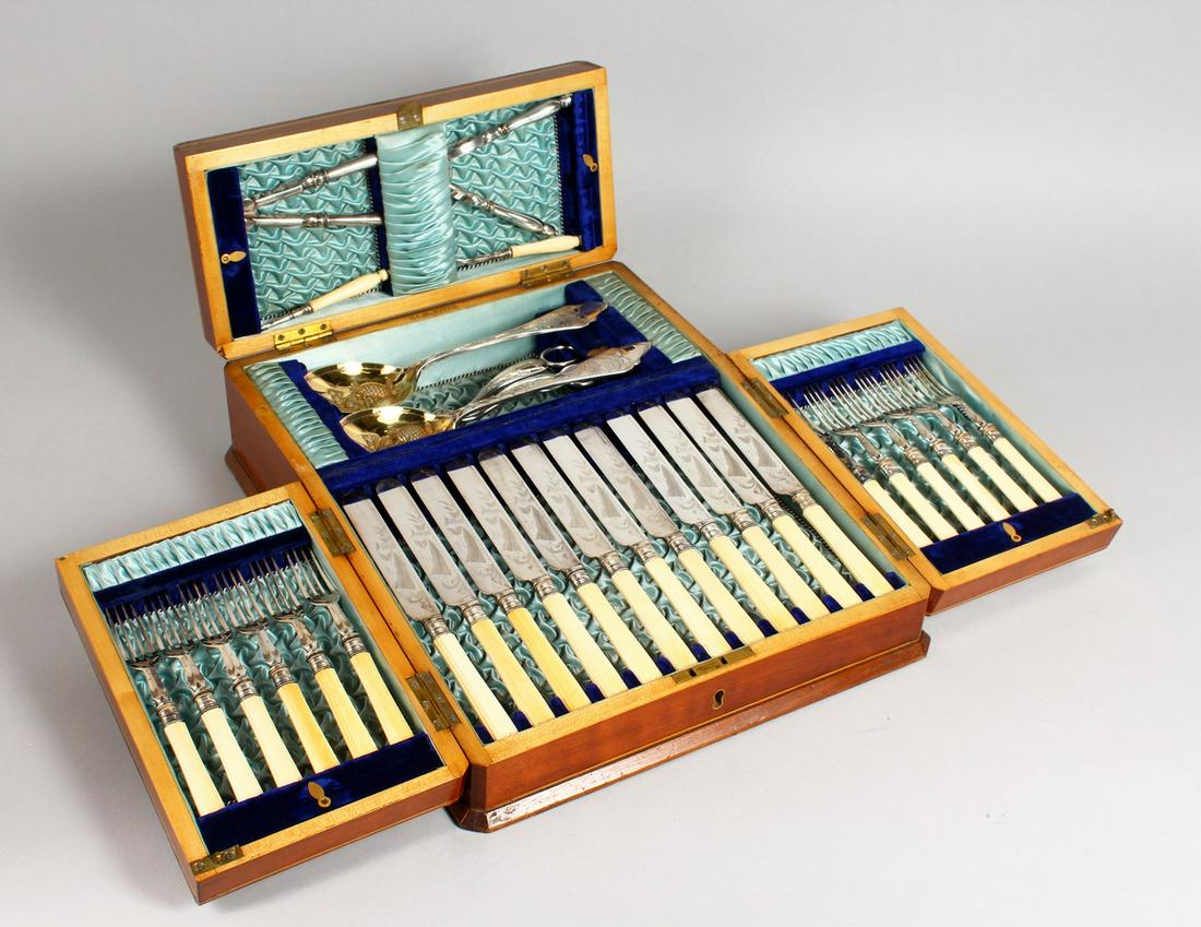 AN UNUSUAL VICTORIAN PLATED CANTEEN, with twelve knives: AN UNUSUAL VICTORIAN PLATED CANTEEN, with twelve knives and forks, nutcrackers, grape scissors and pair of serving spoons, contained in a folding walnut canteen.