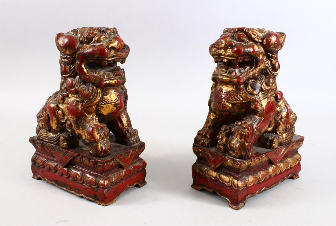 A PAIR OF 19TH CENTURY CHINESE CARVED WOOD & LACQUER: A PAIR OF 19TH CENTURY CHINESE CARVED WOOD & LACQUER FIGURES OF LION DOGS, each modelled upon a carved fixed pedestal base, 25cm high x 11cm wide.