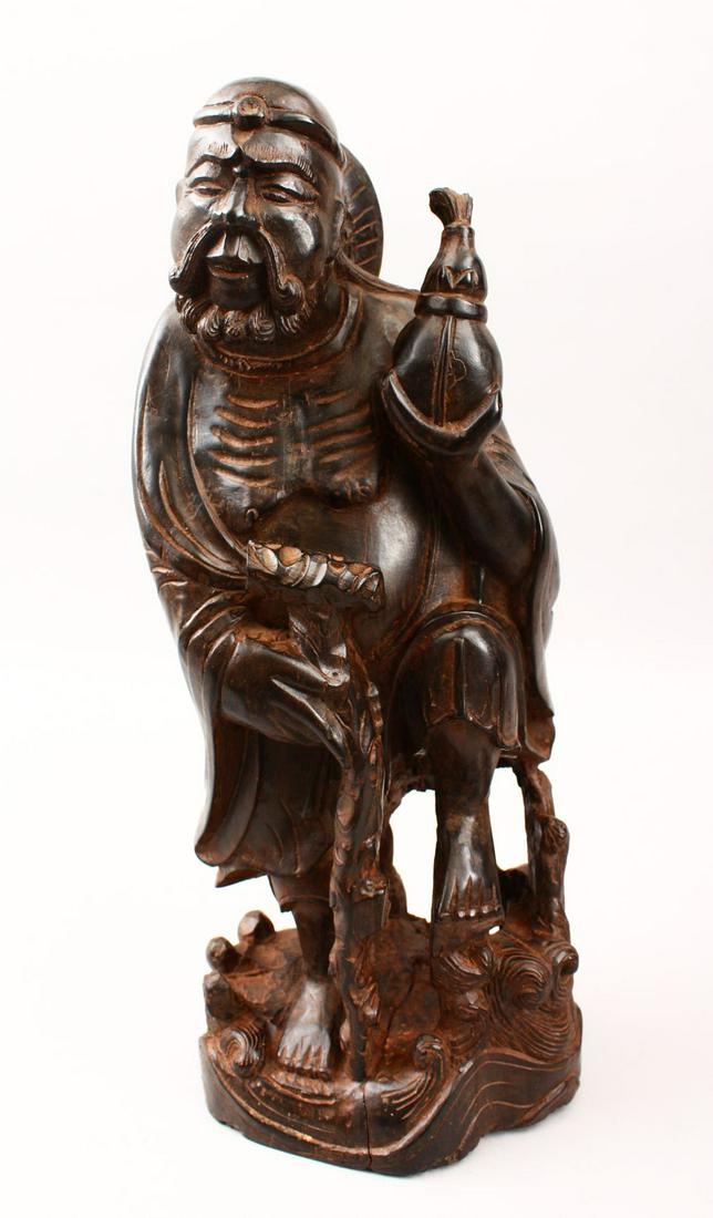 A LARGE 19TH / 20TH CENTURY CHINESE CARVED HARDWOOD: A LARGE 19TH / 20TH CENTURY CHINESE CARVED HARDWOOD FIGURE OF AN IMMORTAL, possibly carved from zitan wood, stood holding a gourd and staff, 38cm high x 14cm wide.