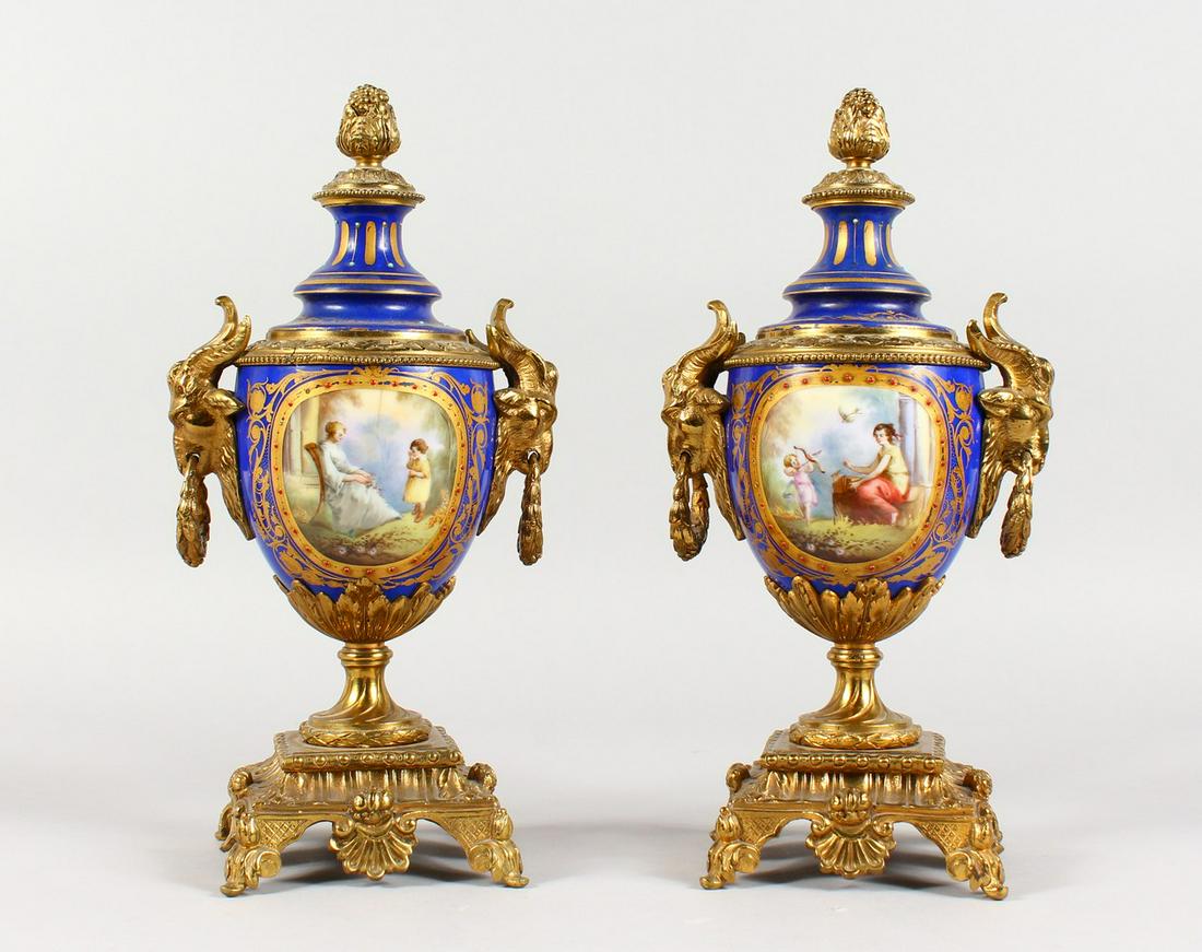 A SUPERB PAIR OF SEVRES PORCELAIN AND ORMOLU URNS AND: A SUPERB PAIR OF SEVRES PORCELAIN AND ORMOLU URNS AND COVERS, painted with reverse scenes of a young girl with cupid and a band of flowers, rich gilded ormolu mounts with rams masks and base. 12ins hi