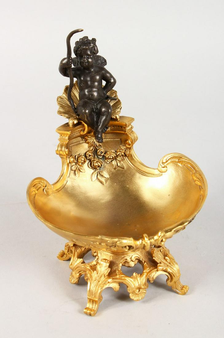 A CLASSICAL STYLE GILT BRONZE TABLE SALT, modelled as a: A CLASSICAL STYLE GILT BRONZE TABLE SALT, modelled as a cherub seated on a shell. 7.5ins high.