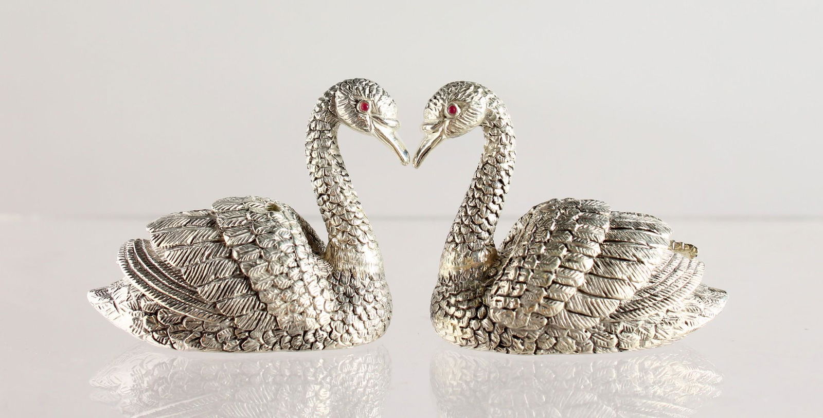 A PAIR OF CAST SILVER PLATED NOVELTY SWAN SALT AND: A PAIR OF CAST SILVER PLATED NOVELTY SWAN SALT AND PEPPERS.
