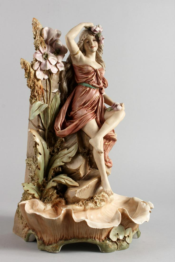 A ROYAL DUX PORCELAIN VASE, depicting a young lady: A ROYAL DUX PORCELAIN VASE, depicting a young lady seated by a wall with flowers and a shell shaped pool below. Impressed mark 600. 15ins.