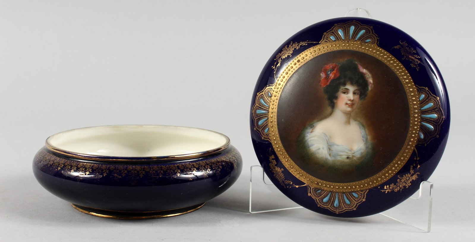 A CONTINENTAL PORCELAIN CIRCULAR BOX AND COVER, rich: A CONTINENTAL PORCELAIN CIRCULAR BOX AND COVER, rich blue ground with gilded decoration, the cover painted with a portrait bust of a young lady. 6.25ins diameter.