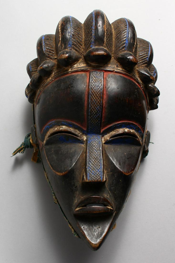 A GOOD CARVED WOOD TRIBAL MASK, with red and blue: A GOOD CARVED WOOD TRIBAL MASK, with red and blue pigment. 11ins high.