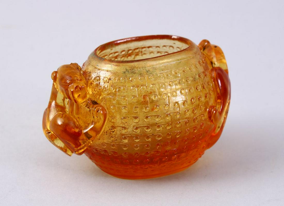 A CHINESE CARVED YELLOW ROCK CRYSTAL LIBATION CUP, with: A CHINESE CARVED YELLOW ROCK CRYSTAL LIBATION CUP, with twin carved chilong handles and stud decoration. 10cm wide.