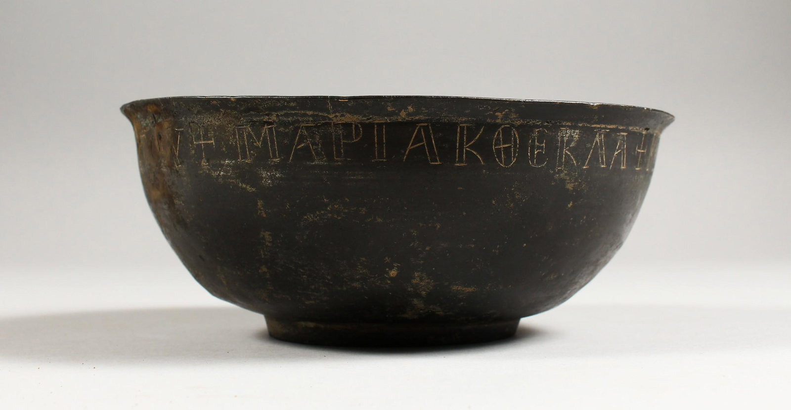A BYZANTINE BRONZE BOWL, the rim with incised: A BYZANTINE BRONZE BOWL, the rim with incised inscription. 7ins diameter.