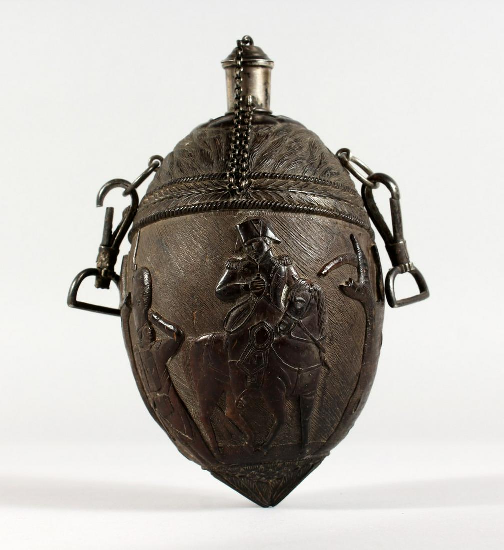 A SUPERB 1800 CARVED COLONIAL COCONUT BOTTLE lavishly: A SUPERB 1800 CARVED COLONIAL COCONUT BOTTLE lavishly carved in relief with Napoleon on horse back, a soldier saluting, the opposite side with shield, helmet and flags, with silver chain, funnel with 