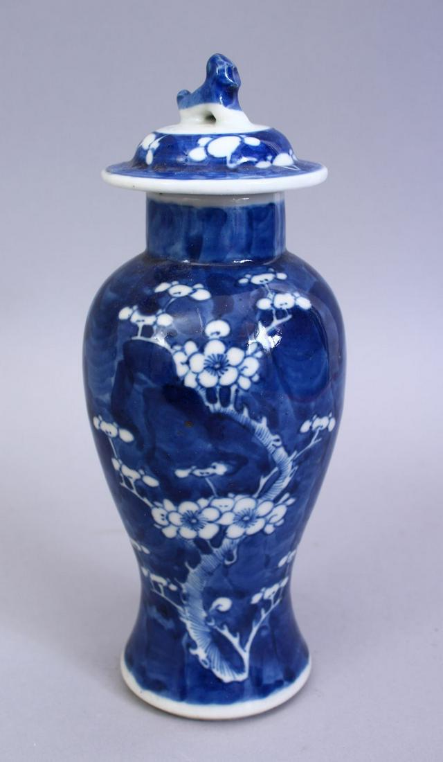 A GOOD 19TH CENTURY CHINESE BLUE & WHITE PORCELAIN: A GOOD 19TH CENTURY CHINESE BLUE & WHITE PORCELAIN PRUNUS VASE & COVER, the body with prunus decoration the lid with a moulded lion dog finial, base with double blue rings, 21cm high