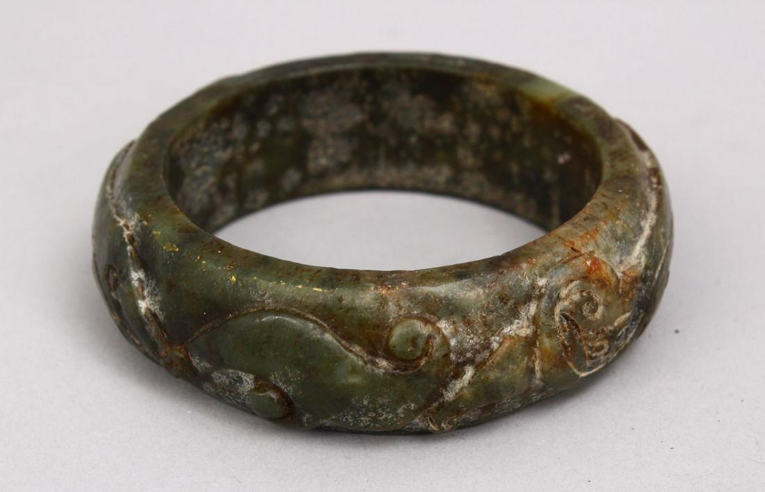 A CHINESE CARVED JADE BANGLE, carved in archaic form, (1 of 2)