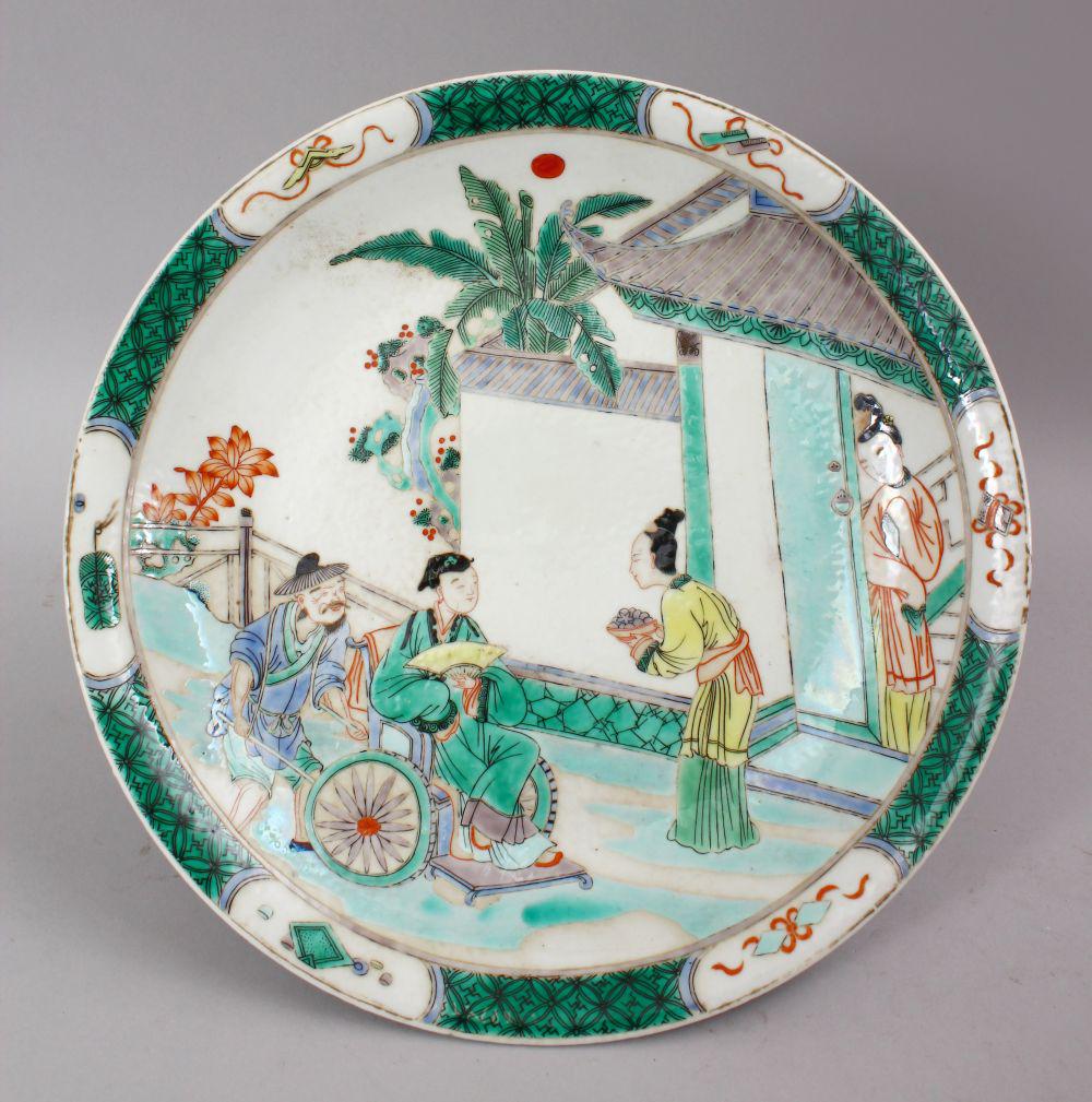 A CHINESE KANGXI STYLE FAMILLE VERTE PORCELAIN DISH,: A CHINESE KANGXI STYLE FAMILLE VERTE PORCELAIN DISH, the dish depciting scenes of figures in garden settings, the verso with a six character mark, 29cm