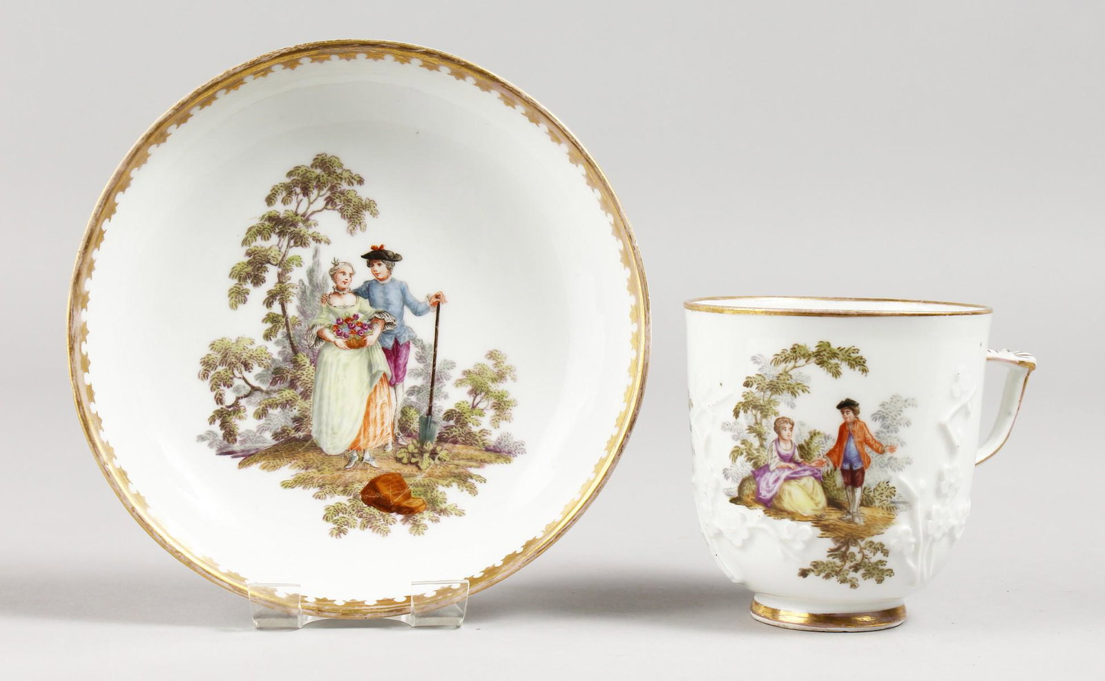 A MEISSEN COFFEE CUP AND SAUCER, prunus moulded ad: A MEISSEN COFFEE CUP AND SAUCER, prunus moulded ad painted with scenes of a courting couple.