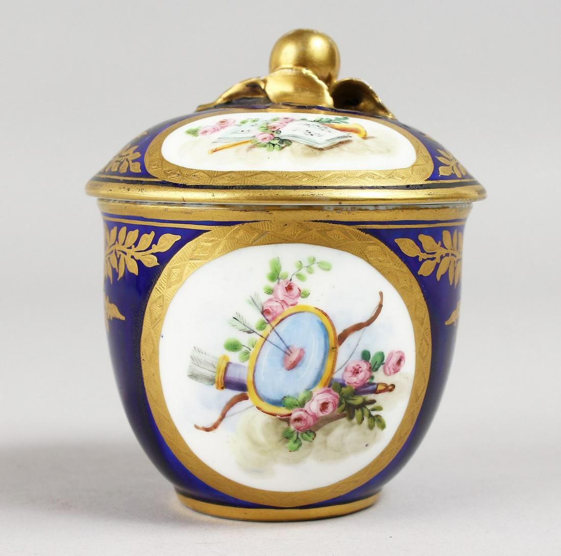 A SMALL SEVRES RICH BLUE GROUND BOWL AND COVER, painted: A SMALL SEVRES RICH BLUE GROUND BOWL AND COVER, painted with cupids and trophies. Sevres mark in blue. 3.5ins.