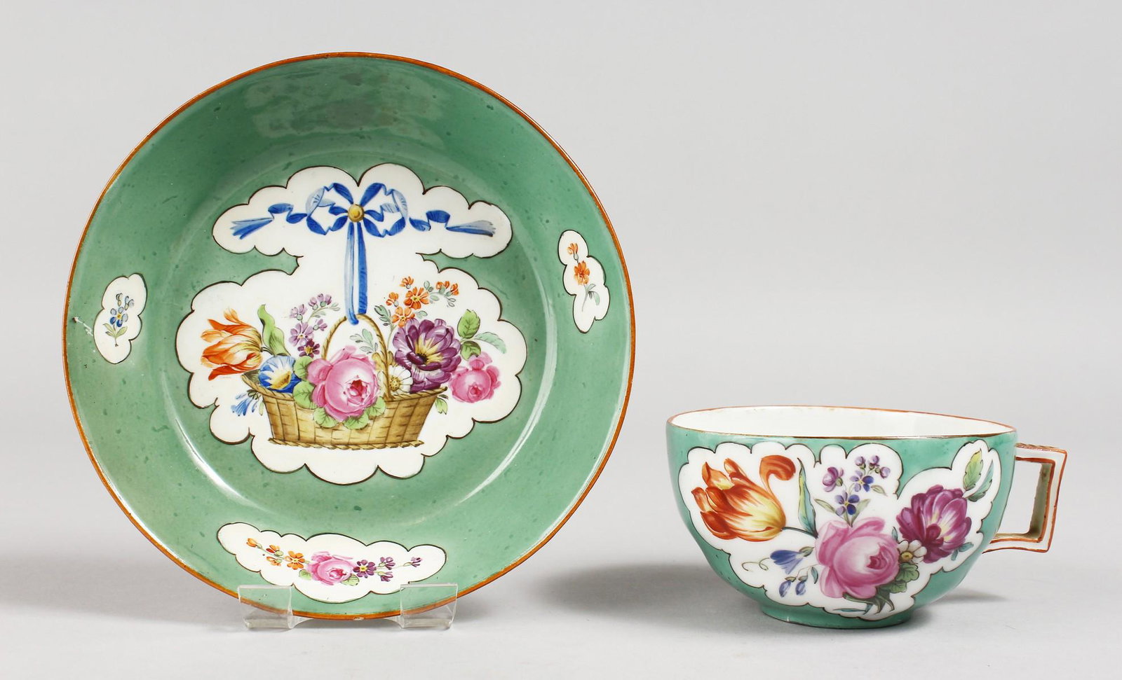 A GOOD MEISSEN GREEN GROUND CUP AND SAUCER painted with: A GOOD MEISSEN GREEN GROUND CUP AND SAUCER painted with baskets of flowers. Mark in blue.