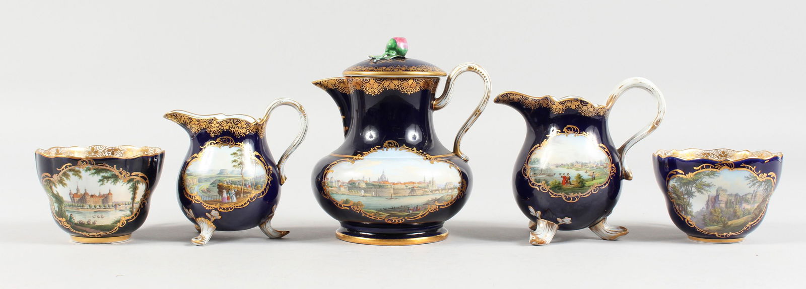 A GOOD MEISSEN RICH BLUE PART CABARET SET, edged in: A GOOD MEISSEN RICH BLUE PART CABARET SET, edged in gilt and painted with scenes including Dresden, comprising lidded jug, two jugs and two cups, all inscribed. Cross swords mark in blue.
