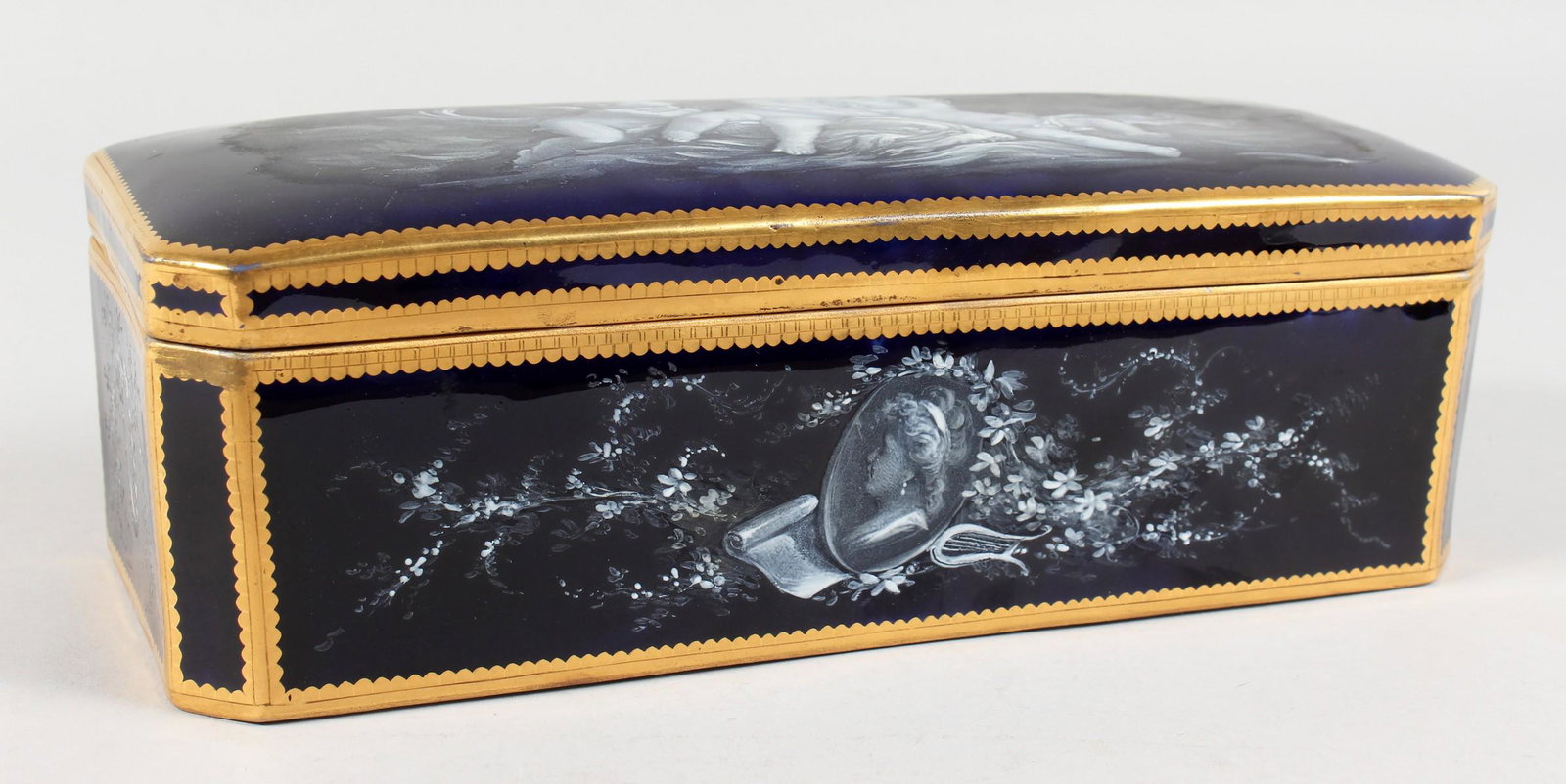 A LARGE LIMOGES PORCELAIN BLUE BOX AND COVER, edged in: A LARGE LIMOGES PORCELAIN BLUE BOX AND COVER, edged in gilt and painted with cupids, the inside with padded velvet. 11ins long.