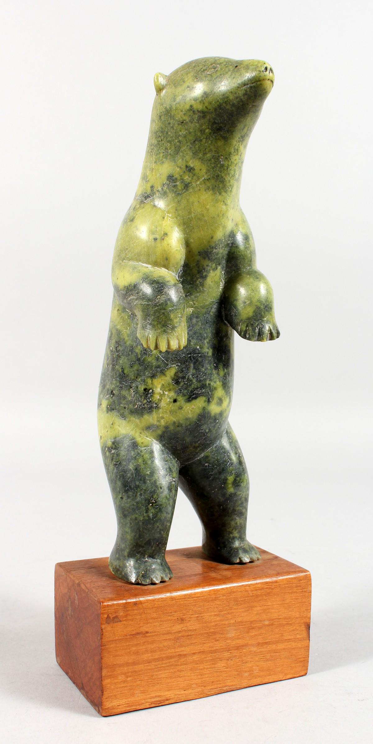 AN INUIT COLOURED STONE CARVING OF A BEAR, standing on: AN INUIT COLOURED STONE CARVING OF A BEAR, standing on its back legs, on a wooden base. 9ins high.